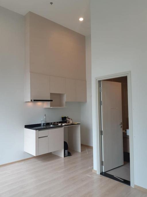 Modern compact kitchen with light wooden flooring and white walls