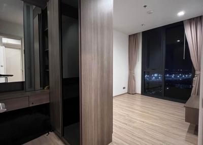 Modern bedroom interior with wooden flooring, large wardrobe, and city view through the window at night