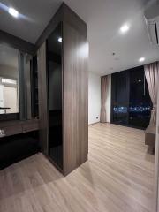 Modern bedroom interior with wooden flooring, large wardrobe, and city view through the window at night