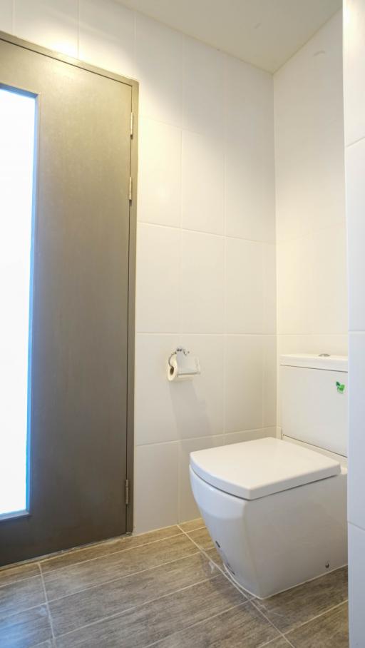 Modern bathroom with wall-mounted toilet and frosted glass door