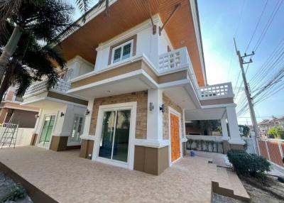 Exterior view of a two-story house with a balcony and palm trees