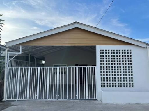 Front view of a modern single-story house with carport and white gate