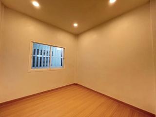 Empty bedroom with wooden flooring and a single window