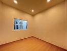 Empty bedroom with wooden flooring and a single window