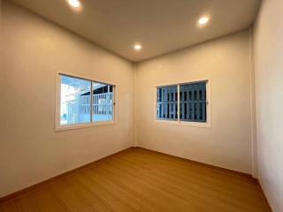 Spacious well-lit bedroom with wooden flooring and two large windows