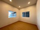 Spacious well-lit bedroom with wooden flooring and two large windows