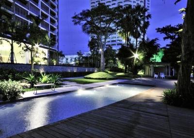 Elegant outdoor common area with illuminated pool and garden at dusk