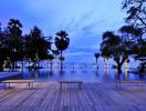 Elegant wooden deck overlooking a tranquil pool with palm trees and ocean view at dusk