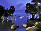 Elegant resort-style outdoor space with lit pool and ocean view at dusk