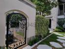 Elegant house exterior with a decorative iron gate and stepping stones leading to the entrance