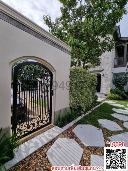 Elegant house exterior with a decorative iron gate and stepping stones leading to the entrance