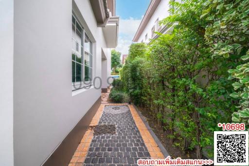 Paved pathway along the side of a modern house with greenery