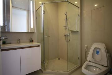 Modern bathroom interior with glass shower enclosure, vanity sink, and toilet