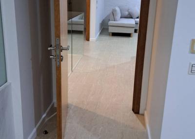 View of a corridor with tiled floors leading towards a bedroom with a visible bed and pillows