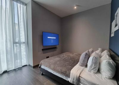 Contemporary bedroom with a wall-mounted TV and large window