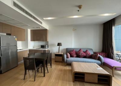 Open concept living room with adjacent kitchen, modern furniture, and hardwood flooring
