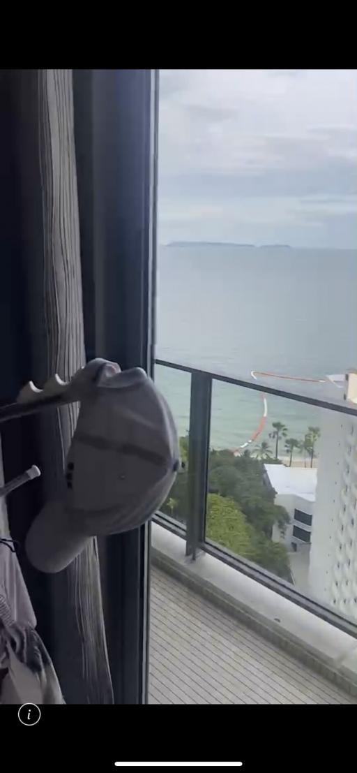 A panoramic sea view seen from the interior of a property through large windows, with a glimpse of a balcony