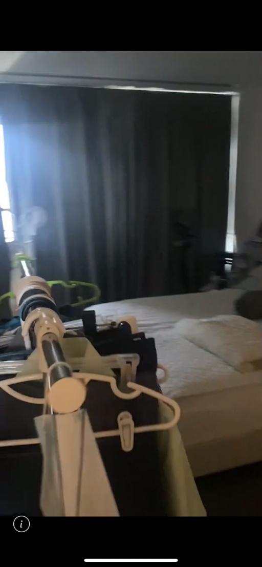 Blurry image of a bedroom with visible ironing board and bed