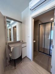 Compact hallway interior with a desk, mirror, and view into bathroom