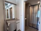 Compact hallway interior with a desk, mirror, and view into bathroom