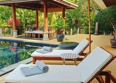 Luxurious backyard with a pool, sun loungers, Thai-style gazebo, and tropical landscaping