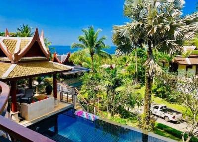 Luxury resort view with traditional architecture, pool, and ocean backdrop