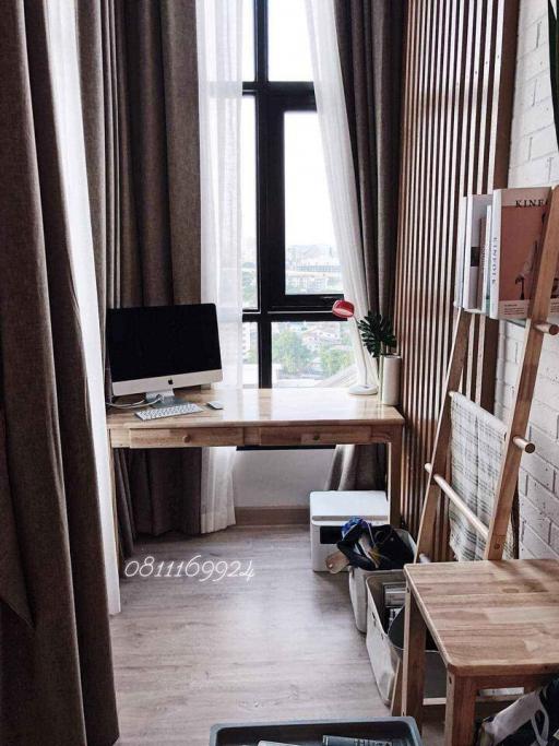 Cozy and well-lit home office space with a large window and wooden furniture