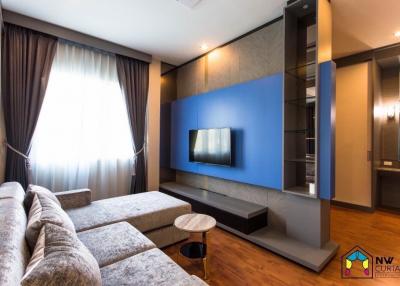 Modern living room with blue accent wall, large sofa, and flat screen TV