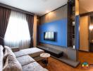 Modern living room with blue accent wall, large sofa, and flat screen TV