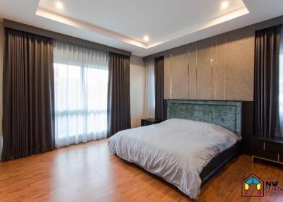 Spacious bedroom with wooden flooring and large window