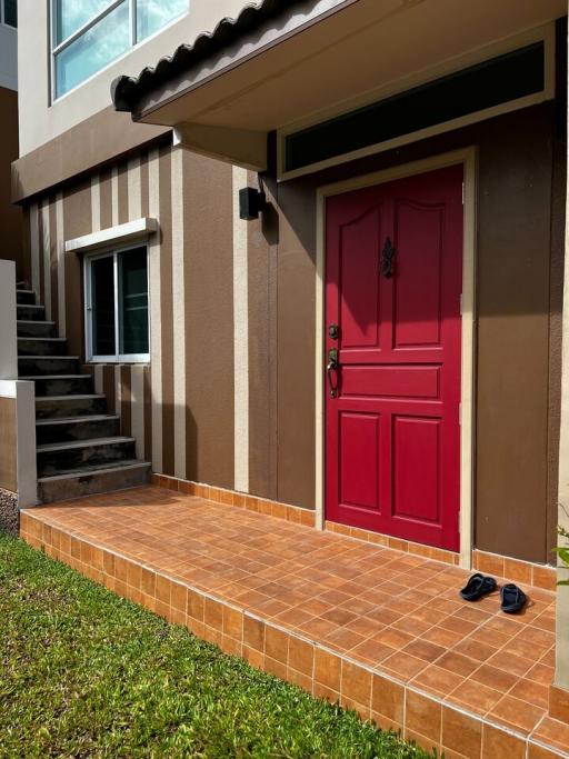 Bright red door at the house entrance with terracotta tiled steps