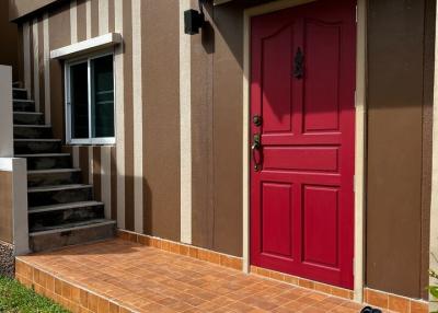 Bright red door at the house entrance with terracotta tiled steps