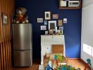 Modern kitchen with stainless steel refrigerator, white storage cabinet, wall-mounted air conditioner, and children's toys