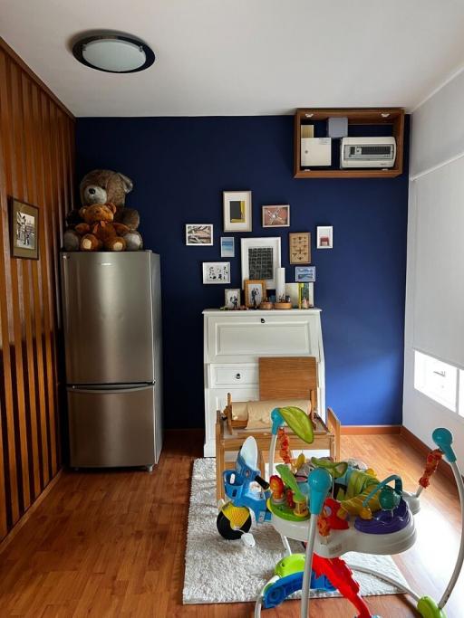 Modern kitchen with stainless steel refrigerator, white storage cabinet, wall-mounted air conditioner, and children