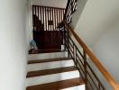 Wooden staircase with white risers and dark wood bannisters inside a house