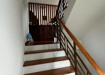 Wooden staircase with white risers and dark wood bannisters inside a house
