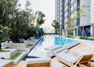 Outdoor swimming pool with lounge chairs in front of a modern apartment building