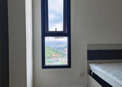 Cozy bedroom with a long vertical window and hillside view
