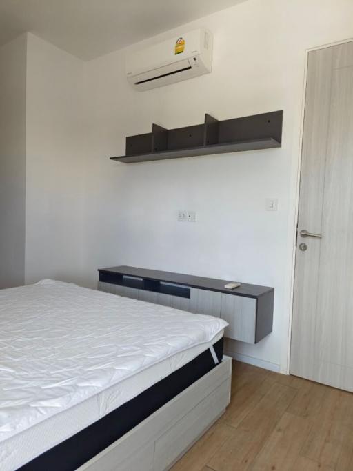 Modern bedroom with white walls, air conditioner, and wooden flooring