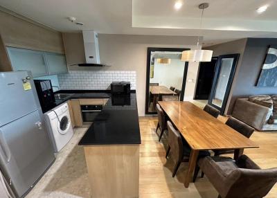 Modern kitchen with stainless steel appliances, wooden dining table, and open plan layout