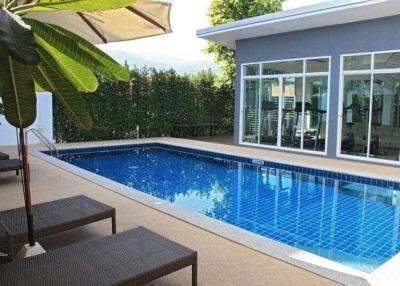 Private swimming pool with patio furniture near a residential building