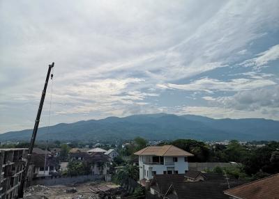 Panoramic view of the surrounding area from a building, featuring mountains in the distance and a construction site