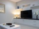 Modern living room with mounted television and white cabinets