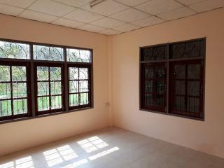 Spacious empty room with tiled floor and large windows with security bars