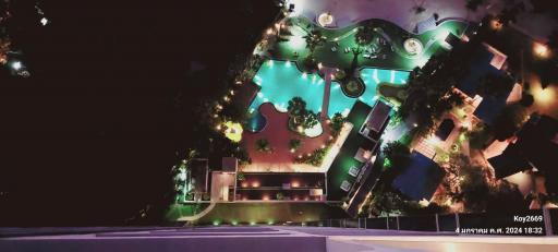 Aerial night view of residential building complex with illuminated pool and garden area