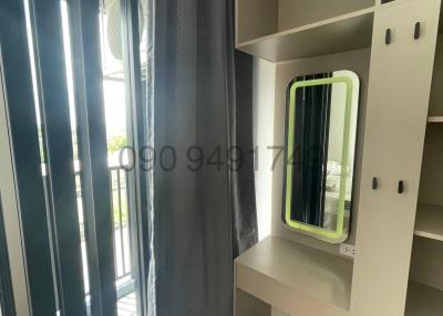 Compact bedroom with built-in wardrobe and shelves near a window with curtains