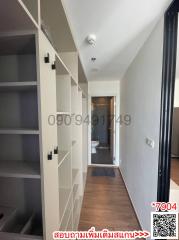 Narrow corridor inside a property with built-in shelves and a view into a bathroom