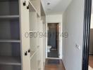 Narrow corridor inside a property with built-in shelves and a view into a bathroom