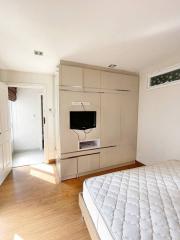 Bright bedroom with built-in wardrobe and wall-mounted TV