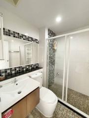 Modern bathroom interior with enclosed glass shower, tiled floors, and white fixtures
